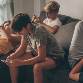 4 Teenager auf der Couch schauen auf ihre Handys