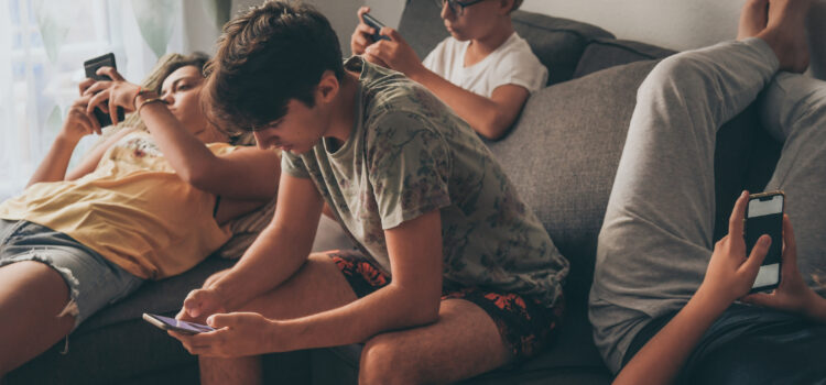 4 Teenager auf der Couch schauen auf ihre Handys