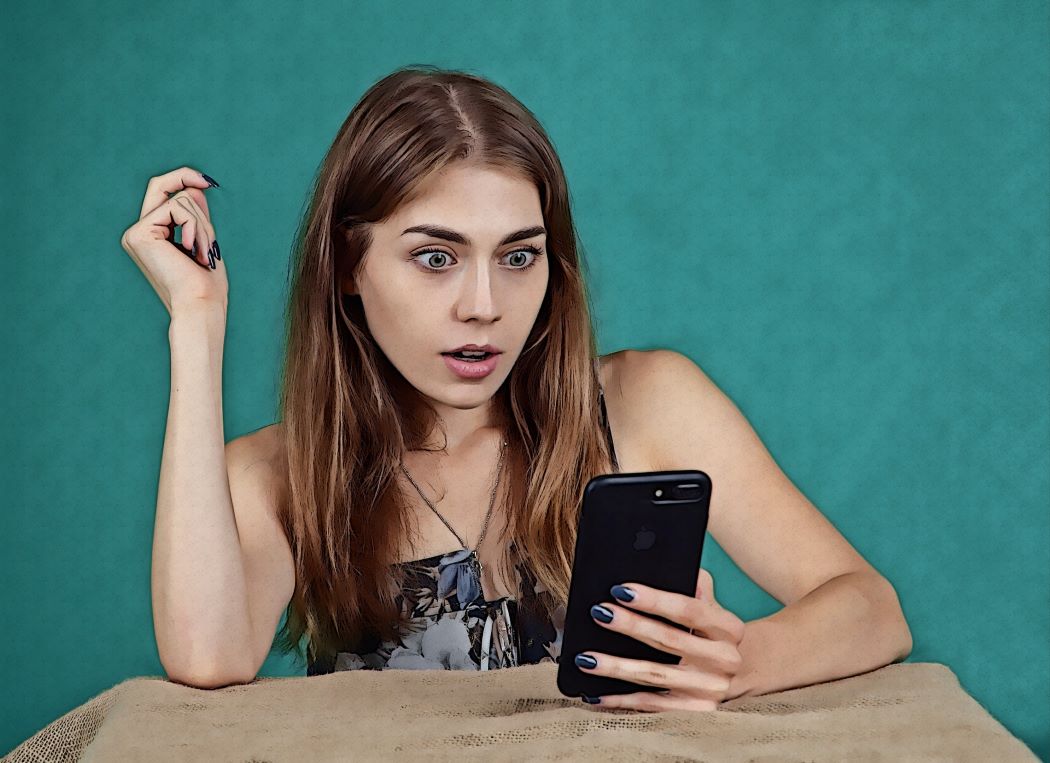 Teeny-Mädchen blickt überrascht auf ihr Smartphone. 