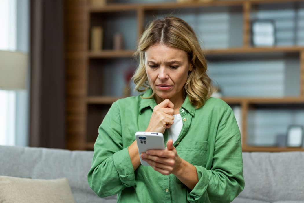 Frau blickt besorgt auf ihr Handy.